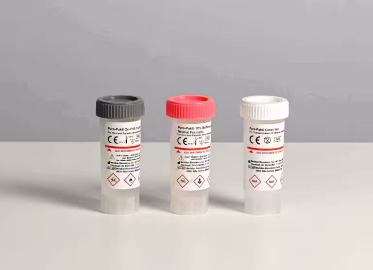 Three laboratory sample bottles with black, red, and white caps on a light surface, labels showing hazard symbols and warning text.