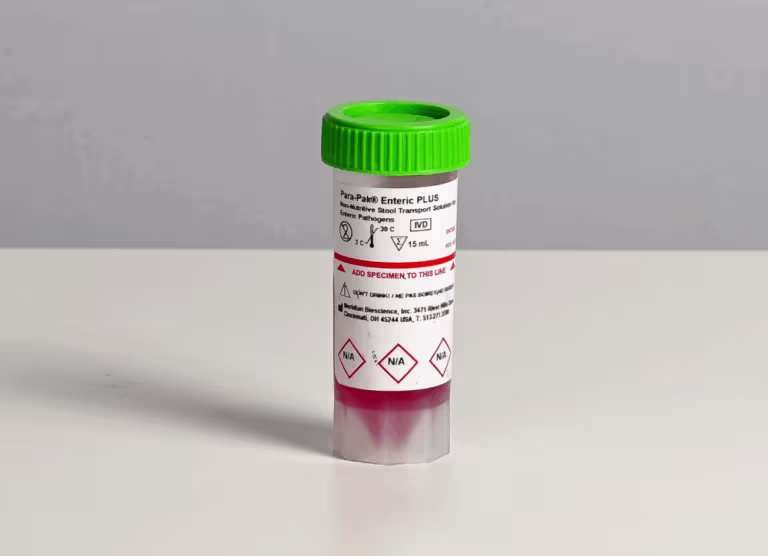 Small specimen container with a bright green screw cap on a white table, labeled with hazard symbols and text.