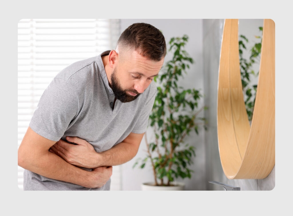 Man with a stomachache, clutching his midsection indoors.