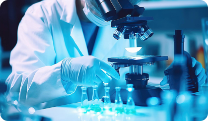 Scientist wearing gloves and a lab coat examines specimens under a microscope in a blue-lit laboratory.