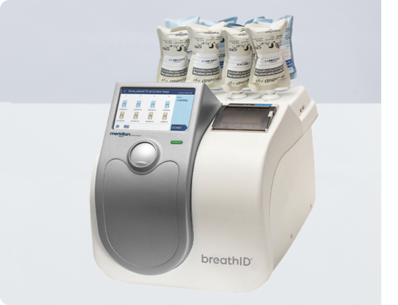 BreathID breath analysis device with sample bags stacked on top and a touchscreen interface on the front.