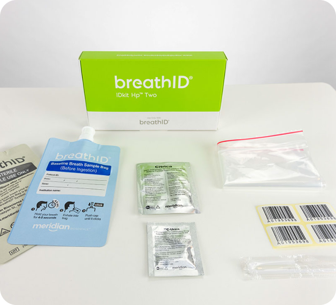 BreathID breath sampling kit on a white surface, showing a green box, blue Baseline Breath Sample Bag, foil pouches, and labeled bags for collection and processing.