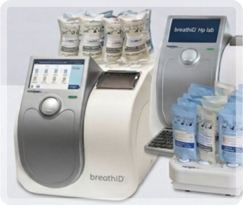 BreathID laboratory breath analyzer with touchscreen, stacked sample vials, and blue cartridge packs nearby.