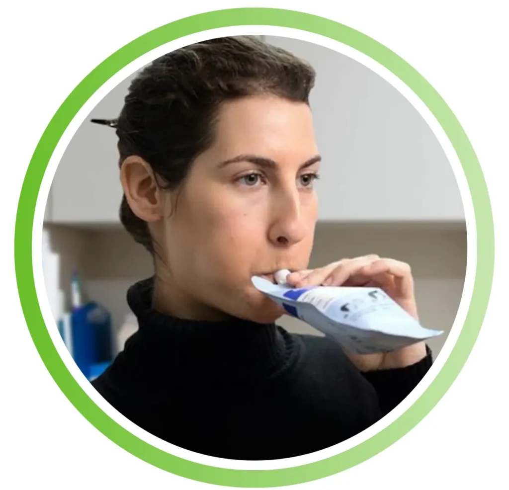 Woman using an inhaler to takemedication, holding the device to her mouth.